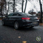 En slank sort Mercedes C300 Coupe parkeret på en fugtig gade, omgivet af efterårsblade, som viser dets luksuriøse design og sporty elegance.