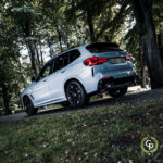 En hvid BMW X3 xDrive30e plug-in hybrid SUV parkeret på en løvstrøet sti, der viser sit slanke design og sporty attitude i et roligt skovområde, der emmer af luksus og