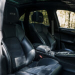 Luksuriøst sort læderinteriør i en luksus-SUV med fremtrædende Porsche Macan GTS-broderi på nakkestøtterne, der fremhæver blandingen af komfort og præstationsorienteret design.