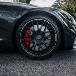 Et nærbillede af et højtydende Mercedes AMG GT Roadster-hjul med en alu-fælg med flere eger og en rød bremsekaliper, prydet med Michelin-dækmærket, sæt
