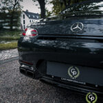 En slank sort Mercedes AMG GT Roadster med eftermarkedsforbedringer af bilens ydeevne parkeret i en vejkant og praler med dens blanke finish og dobbelte udstødninger midt i en urban kulisse.