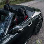 En elegant sort Mercedes AMG GT Roadster med luksuriøse rødt trimmede lædersæder, parkeret udendørs, hvilket fremhæver dets elegante design og højtydende funktioner.