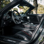 Luksuriøst interiør i en Mercedes AMG GT roadster, med lædersæder med røde syninger, avanceret cockpit med multifunktionsrat og avanceret beklædning.