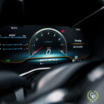 Digitalt instrumentbræt på en Mercedes AMG GT C Roadster, der viser nul hastighed, 18,5°c temperatur, tid og sofistikerede målere, med logoet 'AMG', der fremhæver bilen