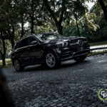 En elegant sort Mercedes GLE350de luksus SUV er parkeret på en brostensbelagt vej, omgivet af frodige grønne områder i rolige parkomgivelser, der viser sit elegante design og førsteklasses tilstedeværelse.