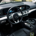 Indvendig visning af en Mercedes GLE350de, der viser et moderne instrumentbræt med digitale displays, rat med betjeningsknapper og luksuriøse finish.
