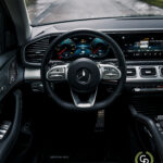 Et luksuriøst hybrid SUV-interiør med et elegant rat med Mercedes-Benz-logoet, digitalt instrumentbræt og moderne midterkonsoldesign i Mercedes GLE350de, alt sammen indbegrebet af sofistikeret bilteknologi og