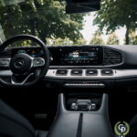 Et indvendigt billede af en hybrid Mercedes GLE350de luksus SUV med et digitalt instrumentbræt, en central infotainment-skærm og elegant klimastyring, alt sammen sat på en baggrund af frodig grønt synligt