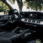 Luksus Hybrid SUV-interiør med et fremtrædende Mercedes-Benz-logo på rattet, der viser et slankt instrumentbræt, moderne infotainmentsystem og poleret midterkonsol med touchpad-kontroller, der symboliserer velhavende biler