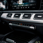 Luksus SUV-interiør med fokus på det avancerede infotainmentsystem og klimastyring med poleret træ- og metalaccenter i Mercedes GLE350de plug-in hybrid, der fremhæver sofistikeret og moderne teknologi