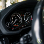 En luksus SUV's digitale instrumentbræt viser et analogt speedometer og omdrejningstæller med en brændstofmåler og forskellige informationsdisplays - alt sammen set gennem et rat.