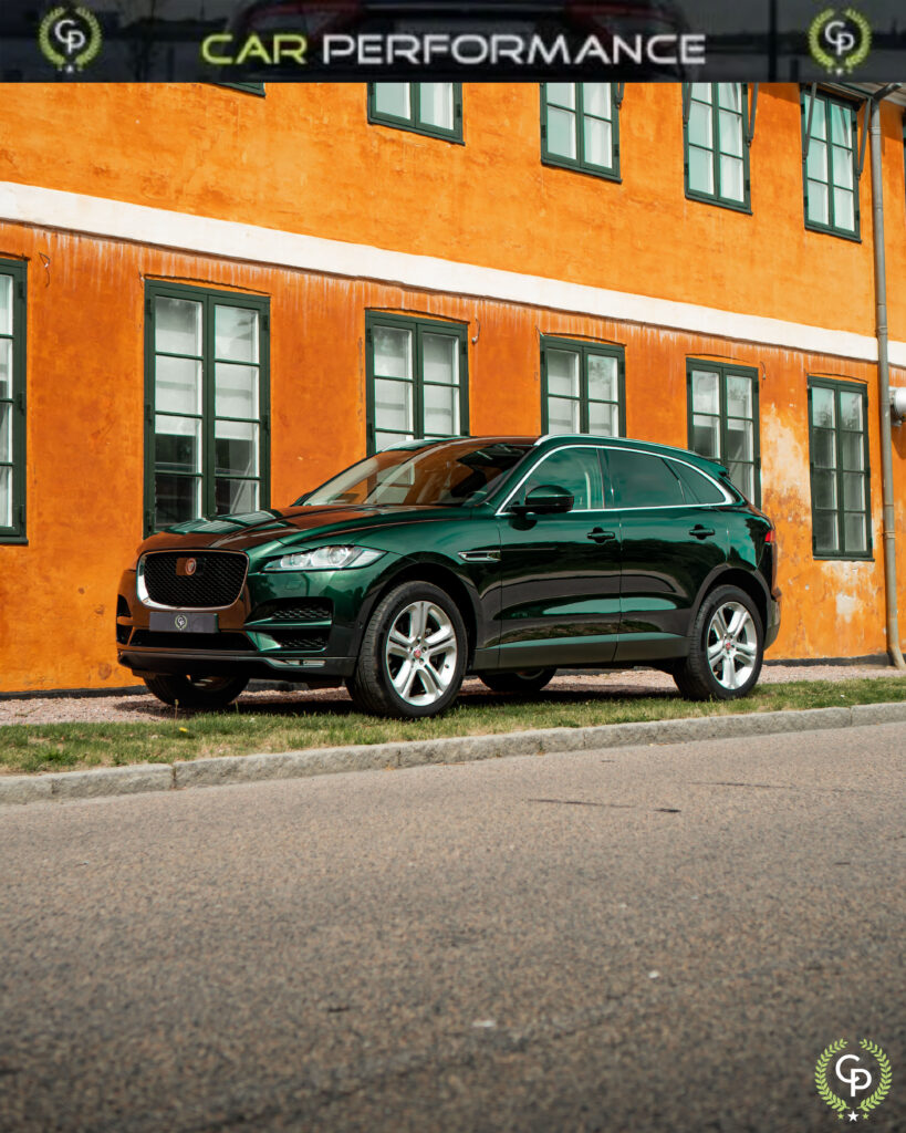 En slank grøn Jaguar F-Pace SUV parkeret på en stille gade, der viser sit luksuriøse design på baggrund af en pulserende orange bygning med en karakteristisk arkitektur.