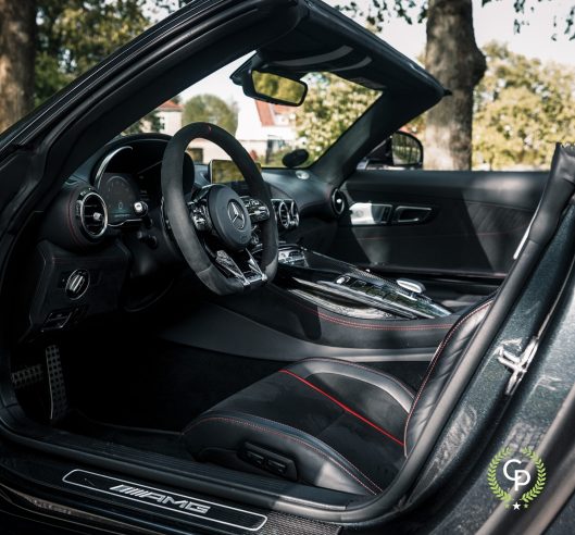 Luksuriøst interiør i en Mercedes AMG GT roadster, med lædersæder med røde syninger, avanceret cockpit med multifunktionsrat og avanceret beklædning.