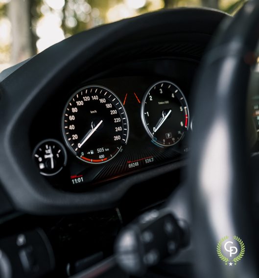 En luksus SUV's digitale instrumentbræt viser et analogt speedometer og omdrejningstæller med en brændstofmåler og forskellige informationsdisplays - alt sammen set gennem et rat.